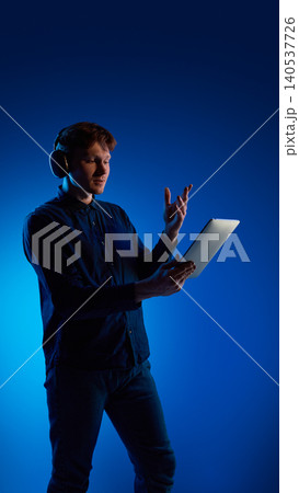 Man using tablet with gesture control in blue studio lighting. Man using tablet with gesture control in blue studio lighting. 140537726