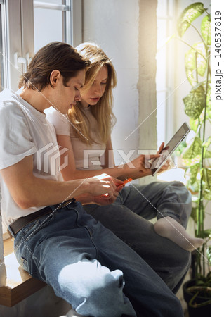 Couple making online purchase with tablet and bank card in sunlit home interior. Couple making online purchase with tablet and bank card in sunlit home interior. 140537819