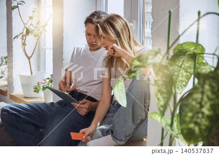 Young couple reviewing tablet and bank card while shopping online at home. 140537837