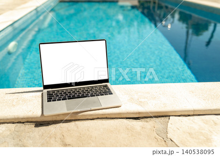Laptop with blank white screen on a swimming pool edge Laptop with blank white screen on a swimming pool edge 140538095
