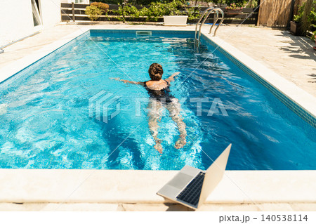 A woman trains in a swimming pool with a laptop. A woman trains in a swimming pool with a laptop. 140538114