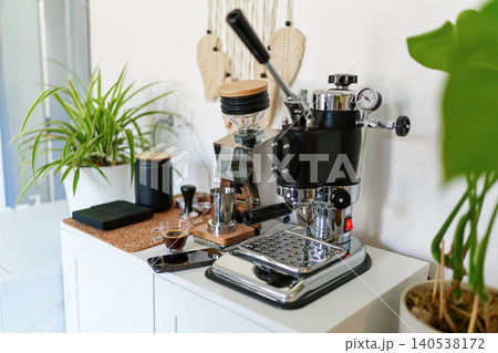 Home barista station with manual lever espresso machine, single dose grinder, and a smartphone on the counter Home barista station with manual lever espresso machine, single dose grinder, and a smartphone on the counter 140538172