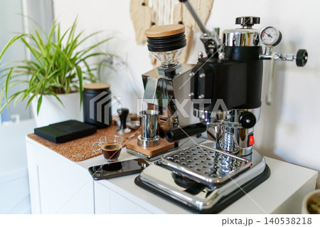 Home barista station with manual lever espresso machine, single dose grinder, and a smartphone on the counter Home barista station with manual lever espresso machine, single dose grinder, and a smartphone on the counter 140538218