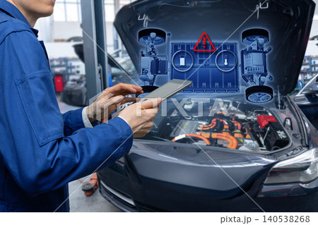 Technician checks the battery pack of an electric car at a service center. 140538268