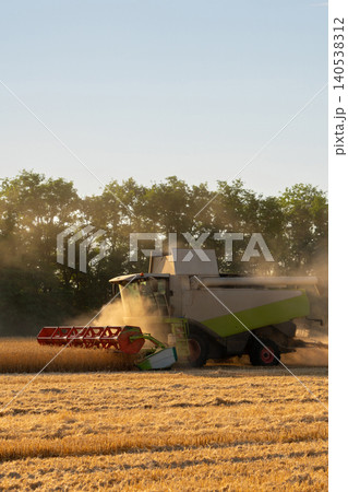 Combine harvester harvests wheat at sunset. Combine harvester harvests wheat at sunset. 140538312