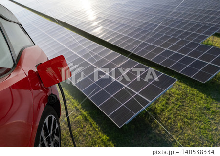 Close up of electric car with a connected charging cable on the background of solar panels.. 140538334