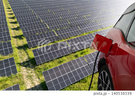Close up of electric car with a connected charging cable on the background of solar panels.. 140538339