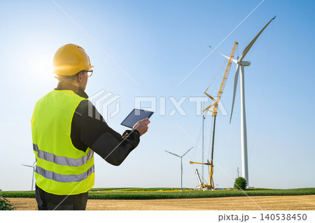 Engineer with digital tablet controls wind turbine installation. Engineer with digital tablet controls wind turbine installation. 140538450