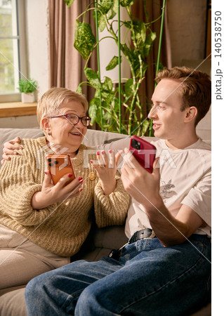 Elderly mother learning online payment from son in sunny living room. 140538750