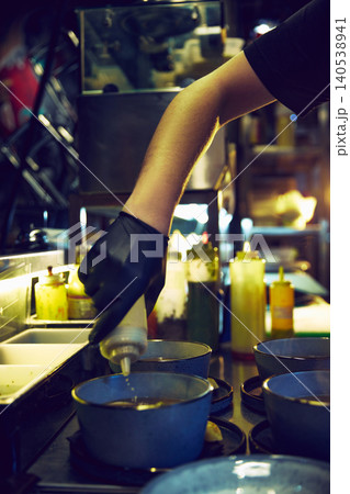 Chef adding sauce to soup bowls during busy restaurant service Chef adding sauce to soup bowls during busy restaurant service 140538941