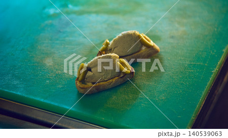 Two creamy toast appetizers with olive garnish on green cutting board Two creamy toast appetizers with olive garnish on green cutting board 140539063