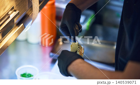Chef spreading savory cream on toasted bread in restaurant kitchen 140539071