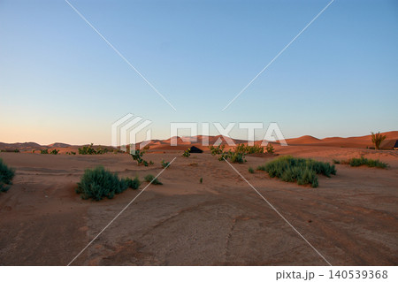 Reddish sand dunes stretch out beneath a clear blue sky in the Merzouga Desert in Morocco. Reddish sand dunes stretch out beneath a clear blue sky in the Merzouga Desert in Morocco. 140539368