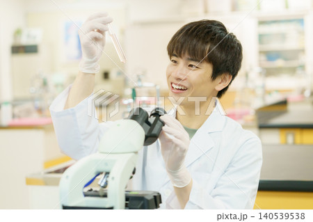 顕微鏡で作業をする白衣を着た若い日本人男性　実験　研究　開発　勉強　 140539538
