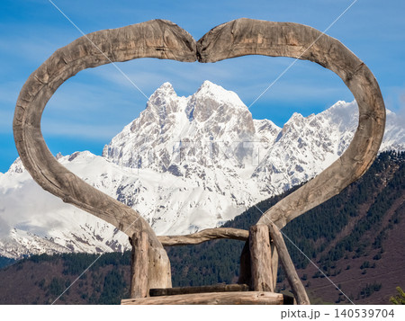 A large, rustic wooden heart frame and snow-capped peaks of Mount Ushba A large, rustic wooden heart frame and snow-capped peaks of Mount Ushba 140539704