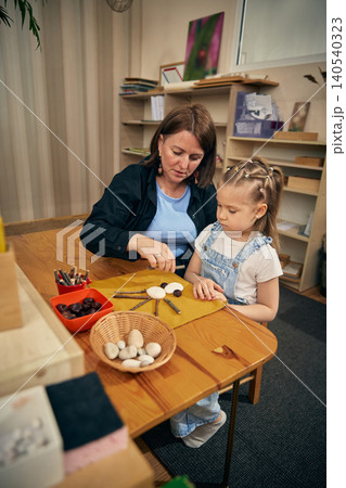 Natural material craft activity helping girl build focus in early learning classroom. Natural material craft activity helping girl build focus in early learning classroom. 140540323