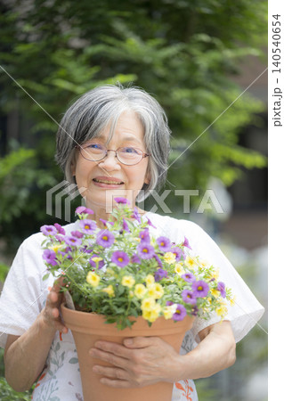 庭の花壇や植木を手入れで園芸(ガーデニング)を楽しむグレイヘアの笑顔のシニア女性　カメラ目線 140540654