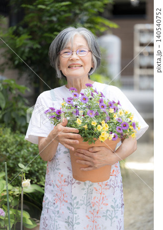 庭の花壇や植木を手入れで園芸(ガーデニング)を楽しむグレイヘアの笑顔のシニア女性 カメラ目線 庭の花壇や植木を手入れで園芸(ガーデニング)を楽しむグレイヘアの笑顔のシニア女性 カメラ目線 140540752