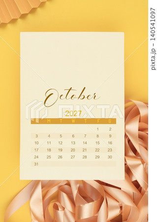 October 2027 calendar page with yellow ribbon on yellow background. October 2027 calendar page with yellow ribbon on yellow background. 140541097