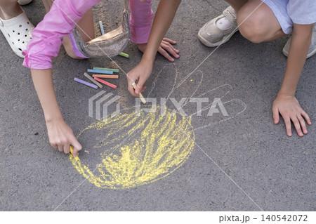 Close-up of a child's hand drawing with colored chalk on the asphalt Close-up of a child's hand drawing with colored chalk on the asphalt 140542072