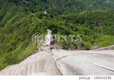 Steep granite cliff with climbing rope on Suraksan mountain ridge path 140542298