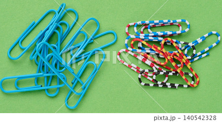 A handful of paper clips lying haphazardly on a green paper background A handful of paper clips lying haphazardly on a green paper background 140542328