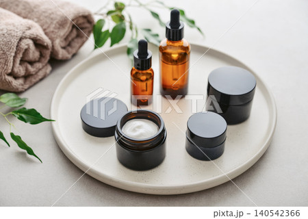 Natural skincare and beauty treatment concept with amber glass cosmetic containers arranged on a round tray. Natural skincare and beauty treatment concept with amber glass cosmetic containers arranged on a round tray. 140542366