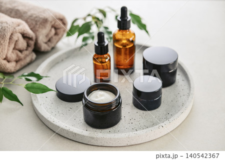 Natural skincare and beauty treatment concept with amber glass cosmetic containers arranged on a round tray. 140542367