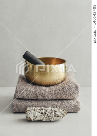 A bright, minimal wellness composition featuring a singing bowl surrounded by folded towels, tingsha bells, and healing crystals A bright, minimal wellness composition featuring a singing bowl surrounded by folded towels, tingsha bells, and healing crystals 140542408