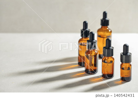 Amber glass dropper bottles of different sizes arranged in ascending order from smallest to largest on light background. Amber glass dropper bottles of different sizes arranged in ascending order from smallest to largest on light background. 140542431