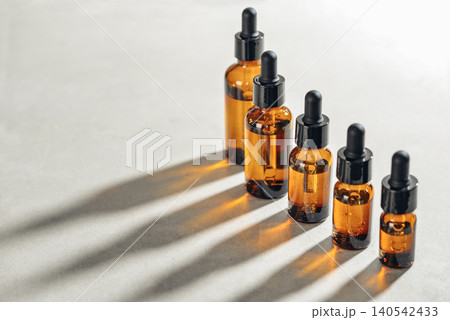 Amber glass dropper bottles of different sizes arranged in ascending order from smallest to largest on light background. 140542433