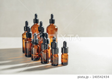 Amber glass dropper bottles of different sizes arranged in ascending order from smallest to largest on light background. 140542434