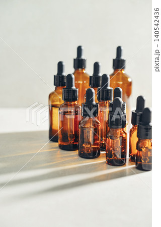 Amber glass dropper bottles of different sizes arranged in ascending order from smallest to largest on light background. Amber glass dropper bottles of different sizes arranged in ascending order from smallest to largest on light background. 140542436