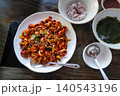 Spicy stir-fried webfoot octopus jukkumi bokkeum with rice and seaweed soup on a wooden table 140543196