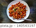 Spicy stir-fried webfoot octopus jukkumi bokkeum with copy space on a wooden table 140543197