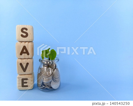 Coins in a glass with growing plant seeds and a cube with the word save written on it. The concept of save money or saving money. 140543250