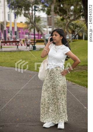 A young girl is talking on her cell phone while walking down a sidewalk A young girl is talking on her cell phone while walking down a sidewalk 140543372
