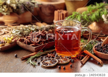 Rustic herbal tea with anise, dried citrus, juniper berries and aromatic spices in a glass mug. 140543610