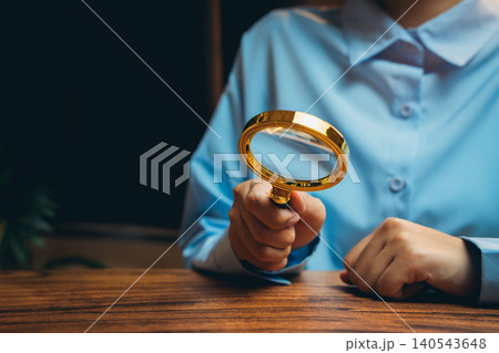 Close-Up of a Person Holding a Magnifying Glass in an Office Setting, Focus on Investigation and Analysis Close-Up of a Person Holding a Magnifying Glass in an Office Setting, Focus on Investigation and Analysis 140543648
