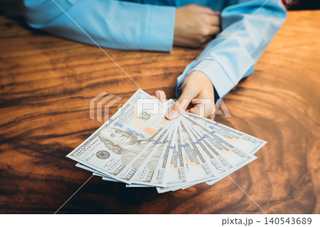 Cash Transaction with Hands Displaying Fresh One Hundred Dollar Bills on Wooden Table Surface Cash Transaction with Hands Displaying Fresh One Hundred Dollar Bills on Wooden Table Surface 140543689
