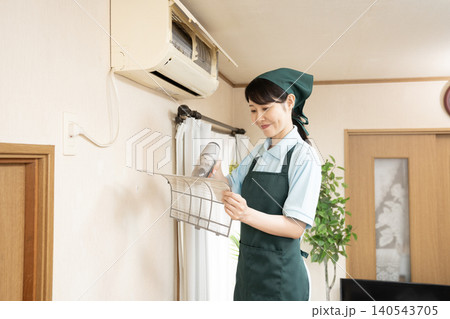 エアコンの清掃をするハウスクリーニングの女性作業員 エアコンの清掃をするハウスクリーニングの女性作業員 140543705
