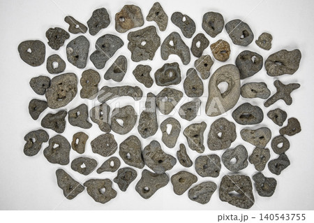Collection of natural hag stones or witch stones on white background with many unique shapes and sizes for luck or protection 140543755