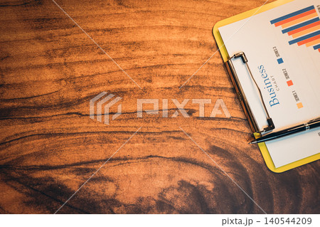 Business concept. Business Data Analysis on a Clipboard with Colorful Graphs and Elegant Wood Table Background 140544209