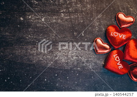 Love concept. Charming Red Hearts with Love Inscription on Dark Rustic Background for Romantic Themes and Celebrations Love concept. Charming Red Hearts with Love Inscription on Dark Rustic Background for Romantic Themes and Celebrations 140544257