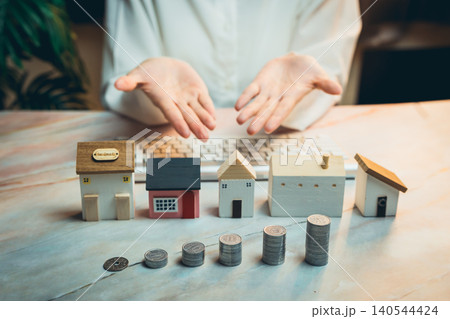 Home buying concept. Hands Open with Model Houses and Coins on Keyboard, Symbolizing Real Estate Investment Concepts and Finances Home buying concept. Hands Open with Model Houses and Coins on Keyboard, Symbolizing Real Estate Investment Concepts and Finances 140544424