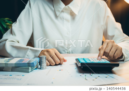 Business concept. Business Professional Using Calculator for Financial Analysis with Cash and Financial Charts on the Table Business concept. Business Professional Using Calculator for Financial Analysis with Cash and Financial Charts on the Table 140544436
