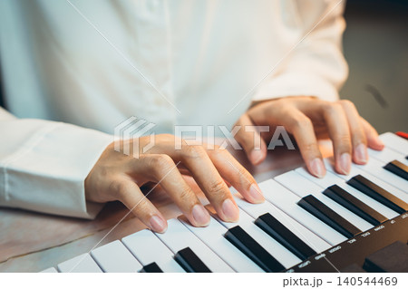 Pianist Concept. Close-Up of Person's Hands Playing Piano Keys on Stylish Music Keyboard in Soft Ambient Lighting 140544469