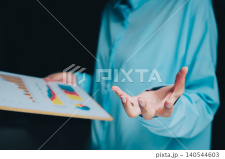 Business professional presenting data sheet with colorful graphs and charts during a corporate meeting session 140544603