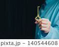 Success key concept. Elegant hand holding a vintage golden key against a dark background, symbolizing secrets and opportunities 140544608