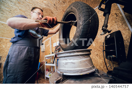 Professional car mechanic replace tire on wheel. Cleaning disc Professional car mechanic replace tire on wheel. Cleaning disc 140544757